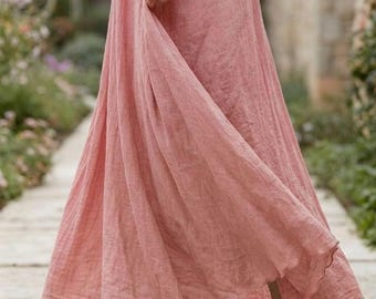 Puede incluir: Una falda larga hasta los tobillos de color rosa empolvado, con cintura elástica y tejido de textura tejida. La falda presenta una silueta amplia y fluida que llega hasta los tobillos, mostrando un color sólido uniforme en toda la prenda.