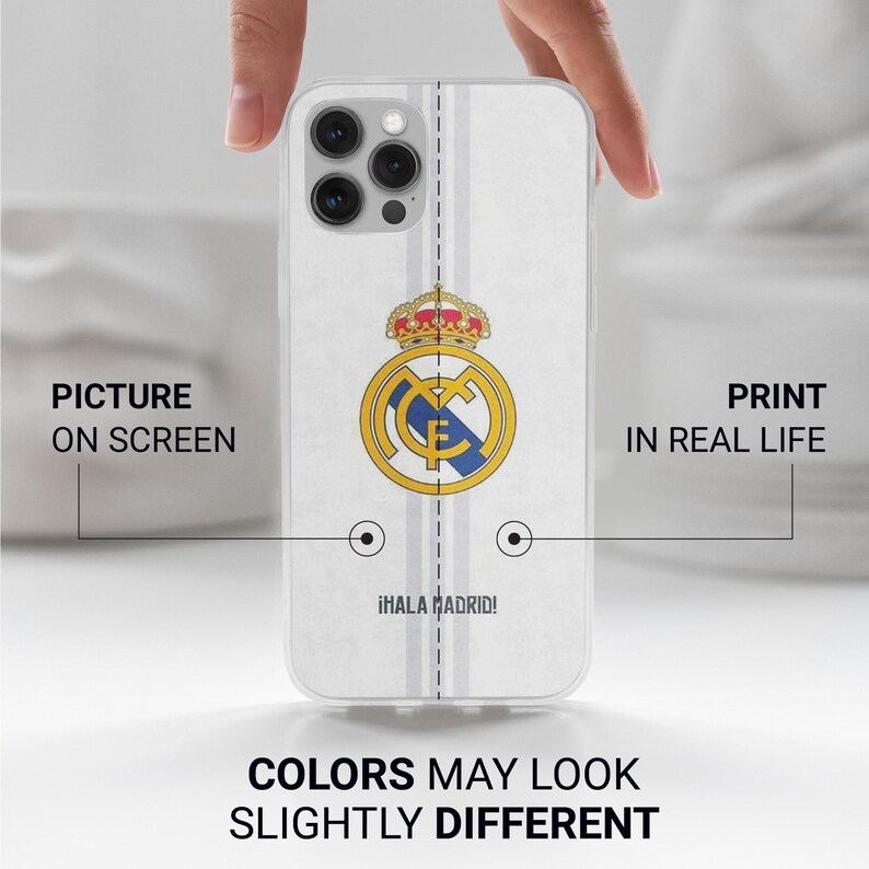 Op de afbeelding: Een doorzichtig smartphonehoesje met het logo van voetbalclub Real Madrid in geel, blauw en rood, gecentreerd op een witte achtergrond met verticale lichtgrijze strepen en de tekst &iexcl;HALA MADRID! in het zwart nabij de onderrand.