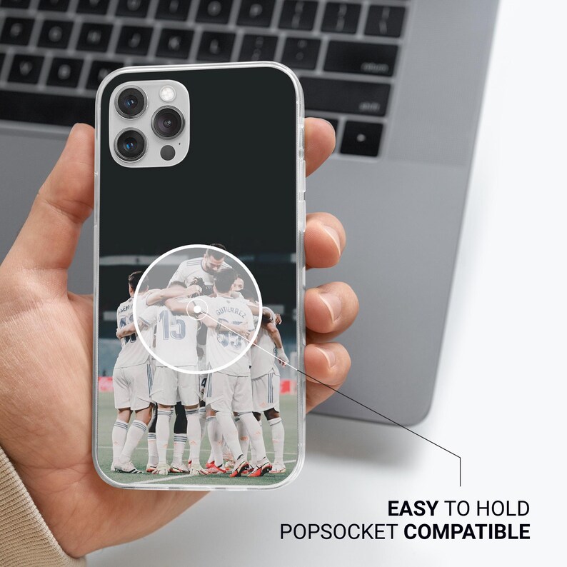 Op de afbeelding: Een doorzichtig smartphonehoesje met een grafische print van een voetbalteam in witte tenues dat op een veld bij elkaar staat. Het hoesje heeft een cirkelvormig gebied voor een gripaccessoire en de tekst EASY TO HOLD POPSOCKET COMPATIBLE.