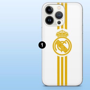 Op de afbeelding: Een witte smartphonehoes met een verticaal goudkleurig streeppatroon in het midden. Het ontwerp bevat een goudkleurig cirkelvormig embleem met een kroon erboven en de letters MCF erin, geplaatst over de verticale strepen op de achterkant.