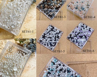 Pode incluir: Sortido de materiais para nail art em caixas de plástico transparente. Os conjuntos incluem pérolas e contas de vários tamanhos e cores, incluindo branco, preto e tons pastel. Cada caixa é rotulada com um número de conjunto.