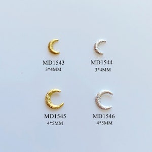 Op de afbeelding: Vier maanvormige bedels in goud- en zilverkleur. Twee zijn goudkleurig, gemarkeerd met MD1543 (3x4mm) en MD1545 (4x5mm). De andere twee zijn zilverkleurig, gemarkeerd met MD1544 (3x4mm) en MD1546 (4x5mm).