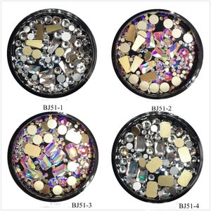 Può includere: Quattro contenitori circolari pieni di strass e elementi decorativi assortiti. Ogni contenitore presenta una disposizione unica di pezzi trasparenti, iridescenti e dorati. I contenitori sono etichettati BJ51-1, BJ51-2, BJ51-3 e BJ51-4.