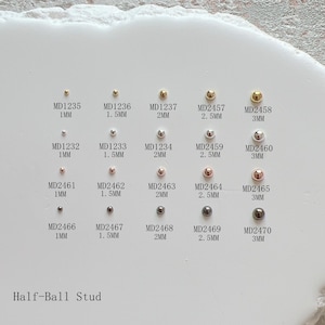 May include: A selection of half-ball stud earrings in gold, silver, and rose gold finishes. Sizes vary from 1mm to 3mm. Each earring is marked with a unique code. The text "Half-Ball Stud" is displayed below the earrings.