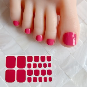 Puede incluir: Pegatinas de esmalte de uñas rosa para una pedicura. Las pegatinas están dispuestas en forma de cuadrícula sobre un fondo blanco.