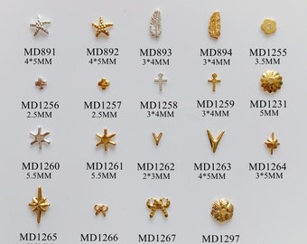 May include: Assortment of gold and silver nail art charms, including stars, leaves, crosses, bows, and flowers. The charms are arranged in rows on a white background. The size of each charm is listed below it, in millimeters.