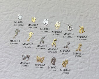 May include: Assortment of gold and silver metal charms in various shapes, including butterflies, mermaids, scorpions, and seahorses. The charms are approximately 4 to 6 centimeters in size.