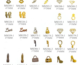 Puede incluir: Surtido de abalorios de metal dorado para el arte de las uñas, que incluyen labios, corazones, zapatos, anillos, peines, frascos de perfume, diamantes y bolsos. Los abalorios están dispuestos en filas y etiquetados con códigos de producto y medidas en pulgadas y milímetros.