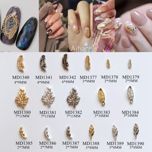 Peut inclure: Assortiment de charmes pour nail art en feuille d'or et d'argent de différentes tailles et formes. Les charmes sont disposés en rangées avec leurs codes produits et leurs dimensions en millimètres correspondants.