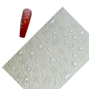 May include: A sheet of white nail decals with silver metallic designs of moons, stars, and suns. The sheet has the text "F979" printed on it.