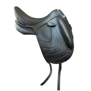 Puede incluir: Una silla de montar de cuero negro con un asiento profundo, un borrén trasero alto y rodilleras prominentes en los faldones. La silla incluye dos latiguillos de cuero largos y delgados que cuelgan de la parte inferior para la cincha.