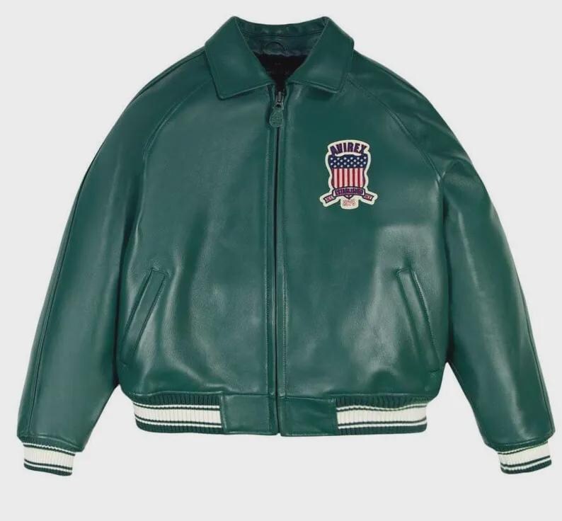 May include: A green leather jacket with a zip-up front, collar, and ribbed cuffs and hem. The jacket features a patch on the chest with a shield design and the text "AVIREX ESTABLISHED 1975". The jacket has two front pockets.