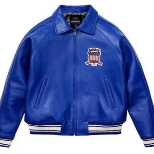 May include: A vibrant blue leather jacket featuring a full-length front zipper, a classic collar, and ribbed cuffs and hem with white and blue stripes. An embroidered patch on the left chest displays the text AVIREX with a flag-inspired shield design.