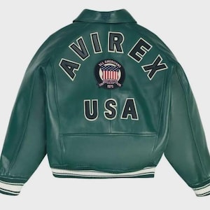May include: A green leather jacket with the word "AVIREX" in white block letters across the back. Below the word "AVIREX" is a patch with the words "ALL AMERICANS ESTABLISHED 1975" and a graphic of the American flag. The word "USA" is below the patch.