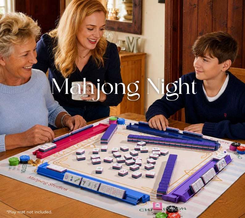 May include: A Mahjong game set with blue, purple, and pink tile holders and tiles. The game is set up on a beige mat with the words "Mahjong Night" printed on it. The image shows three people playing the game.
