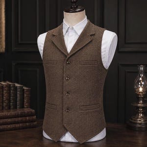 Puede incluir: Un chaleco de tweed marrón con solapa de muesca, cuatro botones frontales y dos bolsillos ribeteados. El chaleco se lleva sobre una camisa blanca de cuello rígido, mostrando un corte estructurado con un acabado de tela texturizada.