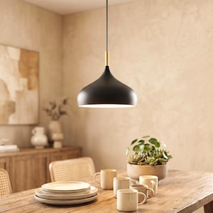 Peut inclure: Une suspension noire mate avec un abat-jour lisse en forme de cloche et un connecteur cylindrique doré. Le luminaire est suspendu par un fin cordon noir et présente une large ouverture à la base diffusant une lumière vive vers le bas.