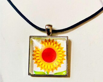Colgante cuadrado de cristal artístico con forma de flor de sol amarilla y collar con cordón de cuero negro.