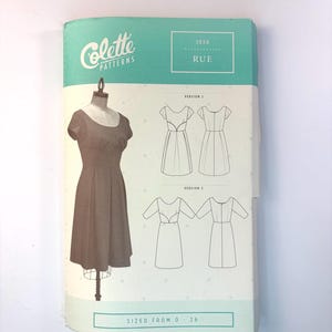 May include: A Colette Patterns sewing pattern envelope for the Rue dress, model 1036. The teal and white cover displays a dress on a mannequin, technical line drawings for Version 1 and Version 2, and the text SIZED FROM 0 - 26.