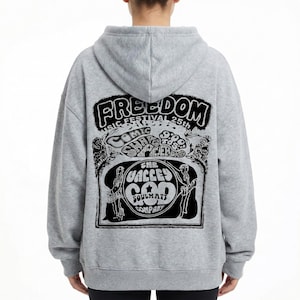 Può includere: Felpa con cappuccio grigia con grafica nera sul retro. La grafica include la parola "FREEDOM" in un font stilizzato, insieme ad altri testi e illustrazioni relativi a un festival musicale.