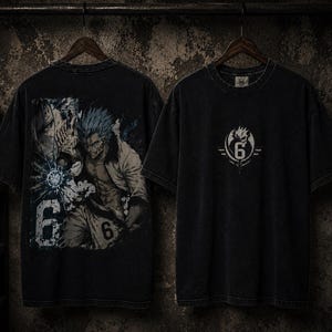 Könnte beinhalten: Ein schwarzes Kurzarm-T-Shirt mit einem Grafikdruck eines Anime-Charakters mit stacheligen Haaren und der Zahl 6 auf der Rückseite. Die Vorderseite des Shirts zeigt ein kreisförmiges Emblem mit der Zahl 6 in der Mitte. Der Stoff hat ein verwaschenes Finish.