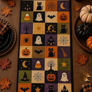 Op de afbeelding: Een rechthoekige gewatteerde tafelloper met een raster van vierkanten met Halloween-thema's, waaronder zwarte katten, oranje pompoenen, witte spoken, vleermuizen, spinnen, spinnenwebben, heksenhoeden, bezems, sterren, manen en spookhuizen.