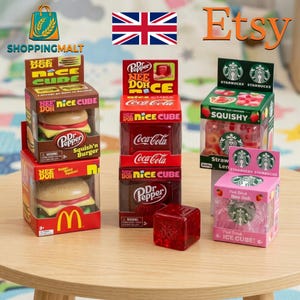 May include: A collection of Nee Doh squishy toys in branded packaging, including two burger-shaped toys in McDonald's and Dr. Pepper boxes, two cube-shaped toys in Coca-Cola and Dr. Pepper boxes, and two Starbucks-themed boxes with squishy items.