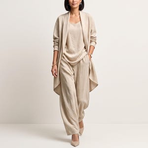 May include: A beige three-piece outfit consisting of a long-sleeved open cardigan, a sleeveless scoop-neck top, and wide-leg trousers. The garments feature a textured fabric finish and are worn with pointed-toe beige heels.