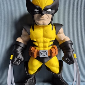 May include: A stylised figurine of a character wearing a yellow and black suit with a matching mask, black gloves, and black boots. The figure features a brown utility belt with a grey X-shaped buckle and three long silver claws extending from each hand.