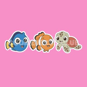 Könnte beinhalten: Ein Set aus drei Aufklebern auf rosa Hintergrund mit einem blauen Doktorfisch mit gelben Flossen, einem orange-weißen Clownfisch und einer grünen Meeresschildkröte mit braunem Panzer. Jede Figur hat große Augen und ein lächelndes Gesicht.