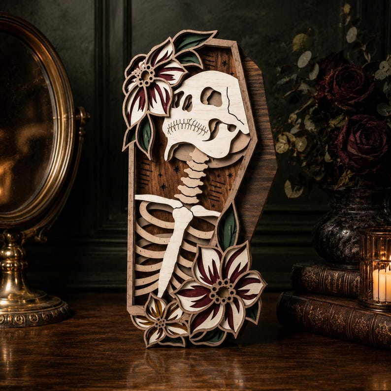 May include: A multi-layered wooden wall art piece shaped like a coffin, featuring a central skeleton torso and skull. The design is accented with layered floral motifs in shades of deep red, dark green, and natural wood tones, with small star details.