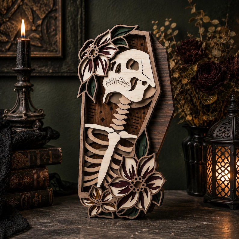 May include: A layered wooden wall art piece shaped like a coffin, featuring a light-colored skull and ribcage skeleton design. The coffin is decorated with dark-toned, multi-layered floral accents in shades of deep red, green, and cream.