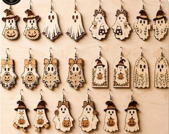 May include: A collection of twenty-two laser-cut wooden ghost earrings arranged on a display board. The designs feature various ghosts wearing hats, holding pumpkins, carrying trick-or-treat bags, or decorated with floral patterns in brown and tan.