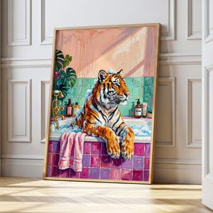 Puede incluir: Una lámina de arte mural enmarcada que muestra un tigre naranja y negro sentado en una bañera llena de burbujas blancas. El baño tiene azulejos cuadrados de color verde azulado, un frente de bañera rosa, una toalla rosa y botellas.