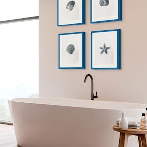 May include: A set of four square wall frames with bright blue borders, each containing a white mat and a black and white illustration of a different sea creature, including various shells and a starfish, displayed above a white oval bathtub.