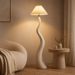 May include: A white, sculptural floor lamp with a wavy stem and a pleated lampshade. The lamp is next to a beige armchair and a small, round side table. The room has a neutral color palette.