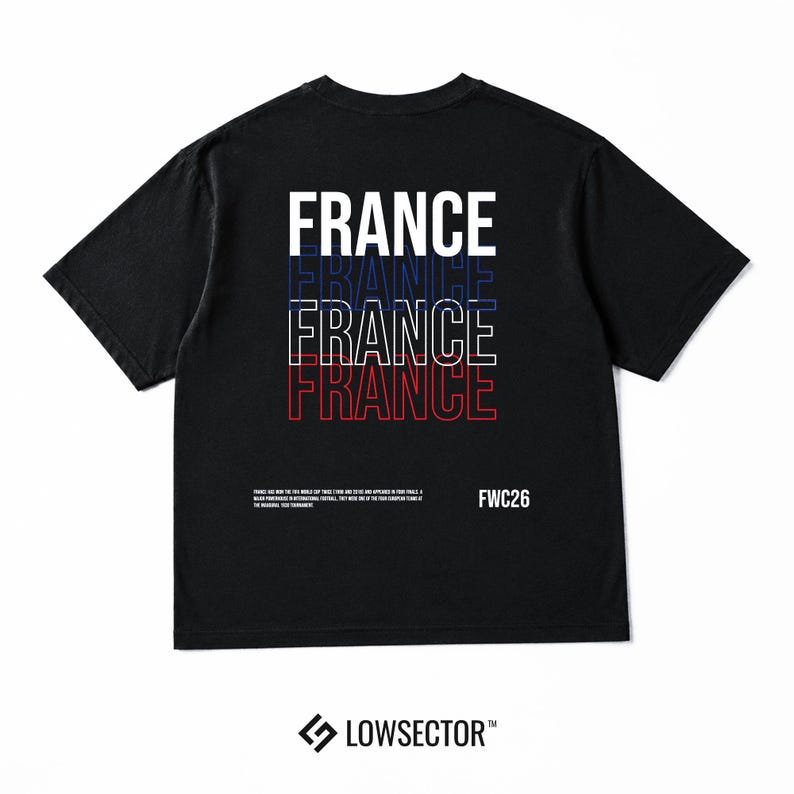 Pu&ograve; includere: Una t-shirt nera a maniche corte con la parola FRANCE stampata quattro volte in un design sovrapposto con contorni bianchi, blu e rossi. Sotto il testo, una piccola scritta bianca riporta FWC26 accanto a un paragrafo sulla storia del calcio.