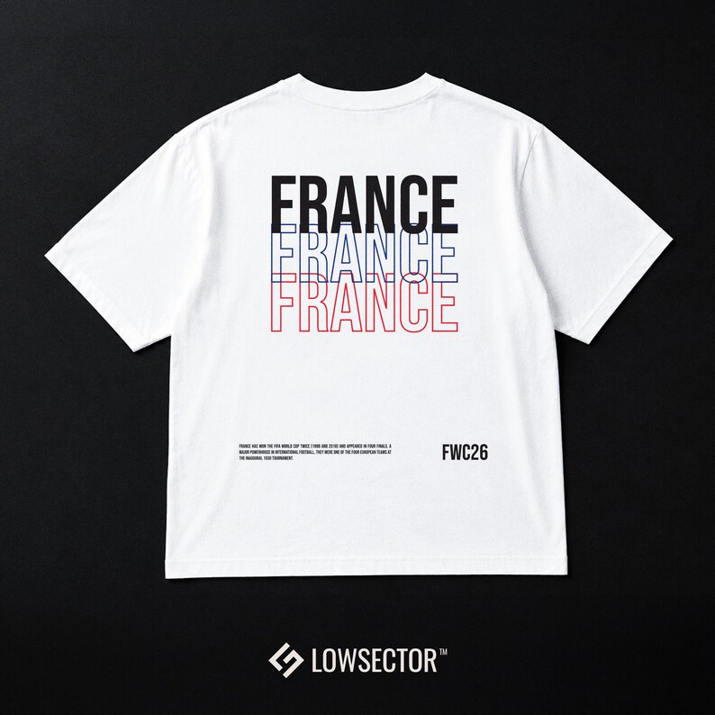 Pu&ograve; includere: Una t-shirt bianca a maniche corte con la parola FRANCE stampata tre volte in nero, blu e rosso. Sotto, un piccolo testo nero fornisce informazioni storiche accanto al testo FWC26. Il nome del marchio LOWSECTOR &egrave; stampato in basso.