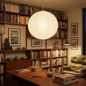 May include: A well-lit home library with a large, round paper lantern hanging from the ceiling. The room features wooden bookshelves filled with books, artwork, and a desk with books and a teapot. A green leather armchair sits in the corner.
