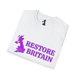 May include: White t-shirt with a purple graphic of the United Kingdom and the words "RESTORE BRITAIN". The shirt has a crew neck and a small black graphic on the upper back. The shirt is folded.