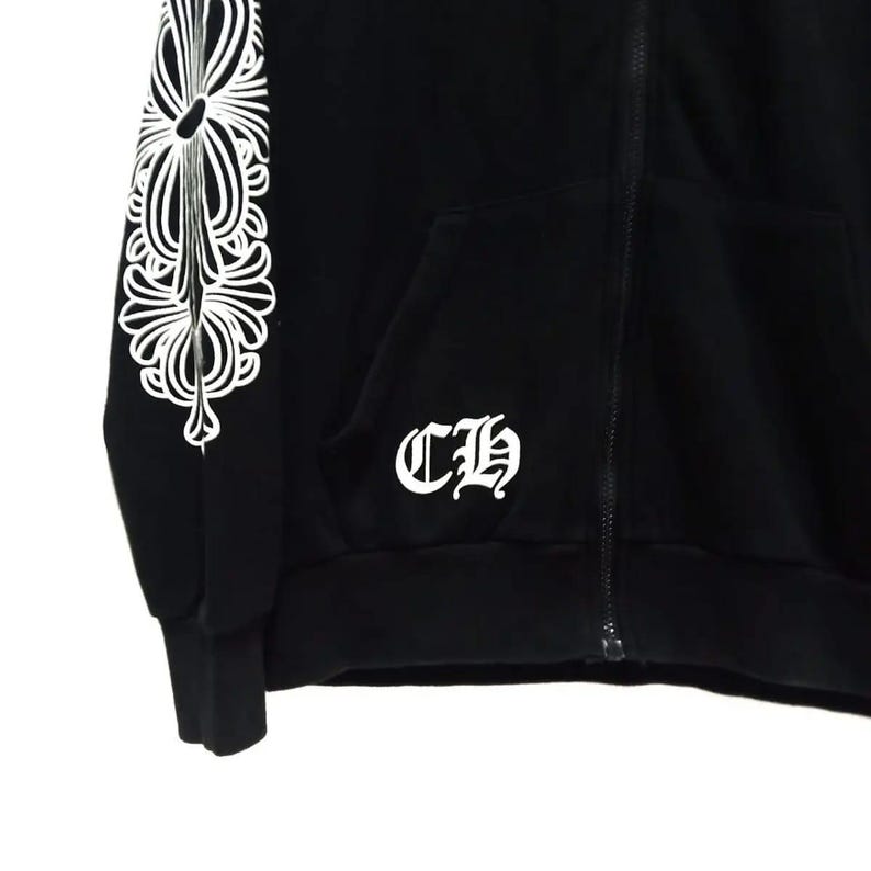 May include: Black zip-up hoodie featuring a white floral pattern on the left sleeve and the letters "CH" on the front. The hoodie has a front pocket and a zip closure.