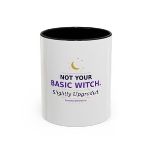 May include: White ceramic mug with a black interior. The mug features the text "NOT YOUR BASIC WITCH. Slightly Upgraded." in purple and black, with a crescent moon and star graphic. The phrase "Brewed differently." is also included.