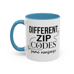 May include: A white ceramic mug with a blue interior and handle. The front features black text that reads DIFFERENT ZIP CODES same nonsense, with two small map pin icons integrated into the lettering on the left and right sides of the text.
