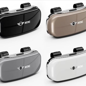 Può includere: Quattro portaocchiali ovali per auto con finitura lucida, ognuno con il logo MINI sulla parte anteriore. I supporti sono disponibili nei colori nero, beige, grigio e bianco e includono ciascuno un meccanismo a clip nero sulla parte superiore.