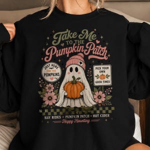 May include: A black long-sleeve sweatshirt featuring a graphic of a ghost wearing a pink beanie and holding an orange pumpkin. The text reads: Take Me To The Pumpkin Patch, Just Here For The Pumpkins, Pick Your Own Good Times, Hay Rides, Happy Haunting.