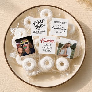 May include: A bowl filled with individually wrapped white ring-shaped candies. Several wrappers feature custom square labels with text including Mint to Be, Olivia & Daniel 10.03.2027, Thank you for celebrating with us, and Custom Logo Design Photo.