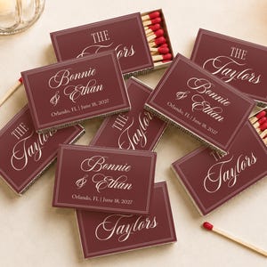 May include: A collection of rectangular matchboxes in deep burgundy with white text. The boxes feature the names Bonnie & Ethan, the location Orlando, FL, the date June 18, 2027, and the phrase The Taylors in a script font with double line borders.