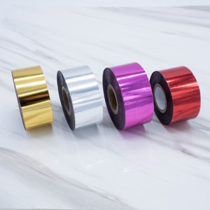 Op de afbeelding: Vier rollen metaalfolietape in goud, zilver, roze en rood.