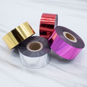 Op de afbeelding: Vier rollen metaalfolietape in goud, zilver, rood en paars.