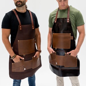 May include: Two leather aprons with brown and tan accents. Each apron has multiple pockets, a chest pocket, and leather straps. The aprons are designed for use in a workshop or kitchen setting.
